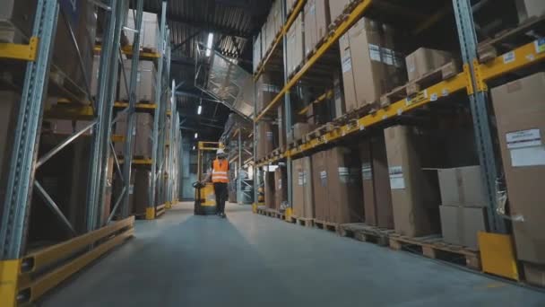 Büyük, modern bir depo. Bir işçi hidrolik forkliftle yük taşır. Stokta modern özel ekipman. — Stok video