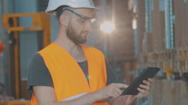 Depoda tabletli bir yönetici malları kontrol ediyor. Büyük bir fabrikanın depo müdürü..