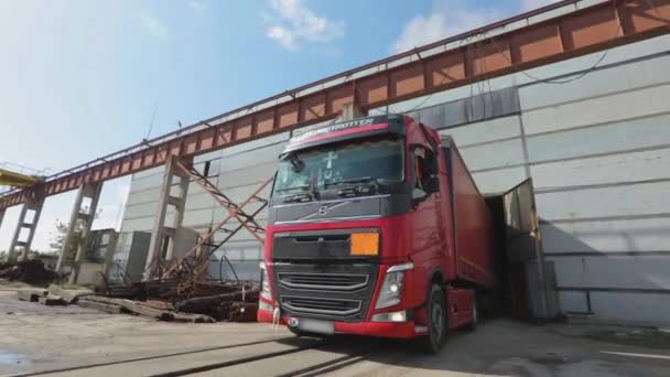 Красный грузовик с красным трейлером едет на склад в ясный солнечный день — стоковое видео