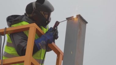 Kaynakçı ağır çekimde, metal kaynaklama işlemi. İnşaat alanındaki kaynakçılar