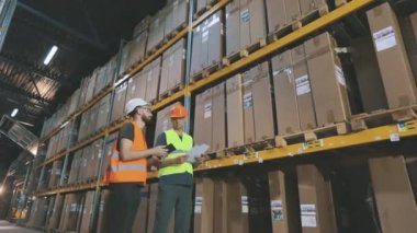Bir depoda iki işçi iş hakkında konuşuyor. Fabrika deposundaki mühendisler.