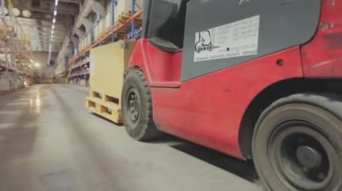 Forklift ahşap bir kutu taşır. Deponun içinde yük taşıyan bir forklift.