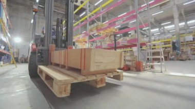 Forklift ahşap bir kutu taşır. Deponun içinde yük taşıyan bir forklift.