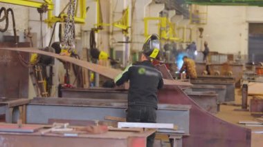 Metal inşaat fabrikası. İnsanlar metal yapılar üreten bir fabrikada çalışıyor.