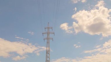 Elektrik taşıma hattı. Elektrik direkleri zaman atlaması, arka planda bulutlar. Yüksek voltajlı kule. Elektrik direklerinin arka planında güzel bulutlar zaman aşımına uğrar