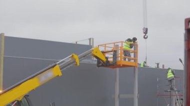 Asansördeki bir adam metal bir yapıya kaynak yapar. İnşaat alanında iş akışı. Metal kaynaklama