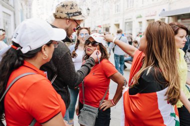 Moskova, Rusya - Haziran 2018 A adam Peru bayrağı kırmızı tişört giymiş bir kadın yüzünde çizer