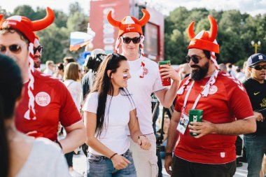 Moskova, Rusya - Haziran 2018 Danimarka taraftarları Dünya Kupası sırasında fan bölgedeki bir Rus kızı ile ulusal renklerde boyanmış Viking kask giyiyor