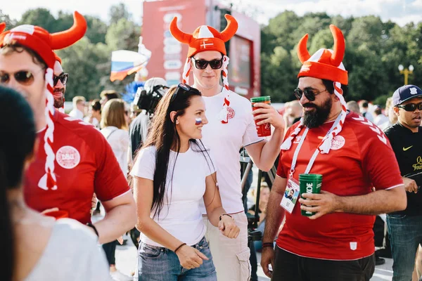 Moskova, Rusya - Haziran 2018 Danimarka taraftarları Dünya Kupası sırasında fan bölgedeki bir Rus kızı ile ulusal renklerde boyanmış Viking kask giyiyor