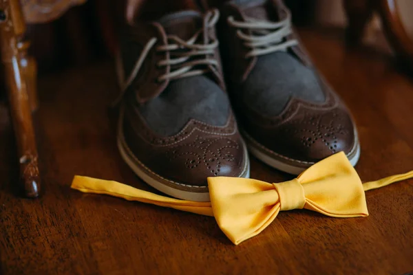 Bir çift kahverengi şık deri erkekler brogues Ayakkabı yanında sarı bir papyon. Damat için aksesuarlar