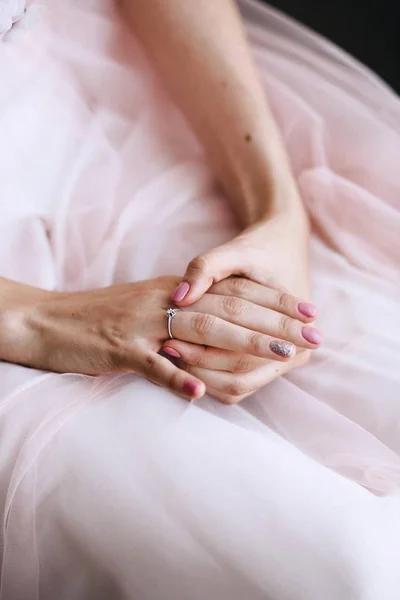 Güzel yumuşak manikür, gelinle elinde bir nişan yüzüğü parmağına elmas yakın çekim ile dokunur. Pembe gelinlik içinde. Dikey