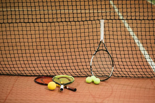 Üç tenis raketleri ve topları kapalı kortta. Yatay