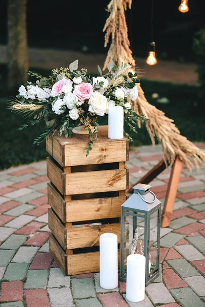Caja de madera pedestal ramo de flores y eucaliptos cerca del candelero y velas blancas. Arco de boda de decoración en estilo rústico — Foto de Stock