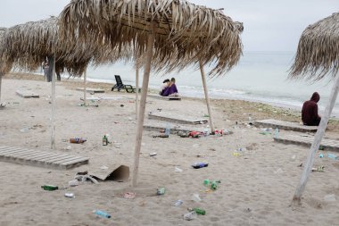 Vama Veche, Romanya - 1 Mayıs 2018: Genç parti bütün gece, Güneş doğmadan önce erken sonra kalan enkaz (özellikle boş şişe), arasında sahilde insanlar