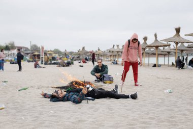 Vama Veche, Romanya - 1 Mayıs 2018: Genç parti bütün gece, Güneş doğmadan önce erken sonra kalan enkaz (özellikle boş şişe), arasında sahilde insanlar