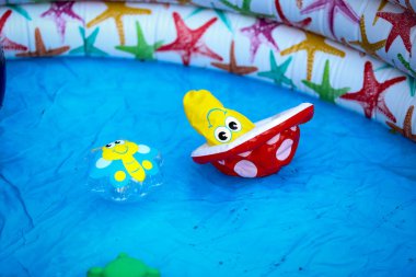 Inflatable colourful kid toys floating in an inflatable swimming pool with shallow water clipart