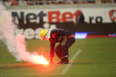 Bucharest, Romanya - 28 Temmuz 2018: İtfaiyeci çimde Dinamo Bükreş destekçileri tarafından ulusal Arena Stadyumu Dinamo ve Fcsb, arasında oyun sırasında atılan meşaleler söndürmek çalışır
