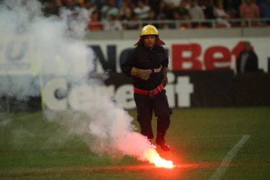 Bucharest, Romanya - 28 Temmuz 2018: İtfaiyeci çimde Dinamo Bükreş destekçileri tarafından ulusal Arena Stadyumu Dinamo ve Fcsb, arasında oyun sırasında atılan meşaleler söndürmek çalışır