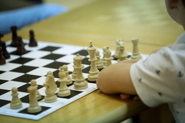 Details of the hands of a 12 years old Chess Master playing with chess pieces on a chess board