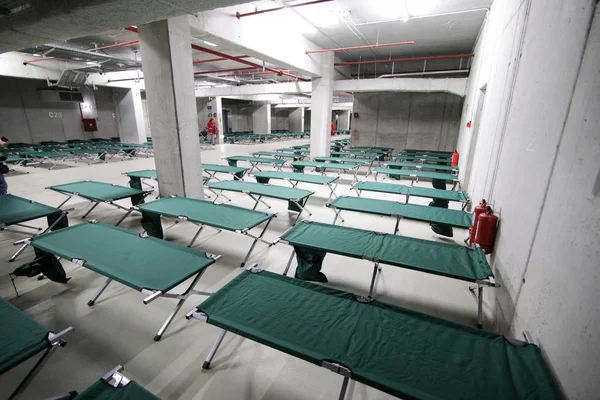 Camp folding cots are being set up in the underground parking of a stadium and wait for refugees, during the drill of a catastrophic earthquake in the city in which there are many victims
