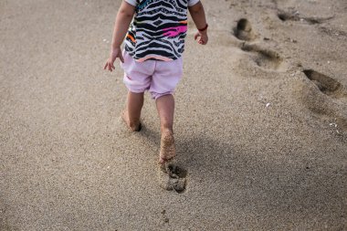 Yalnız çocuk kuma ayak diziniz bırakarak sahilde yürüyor