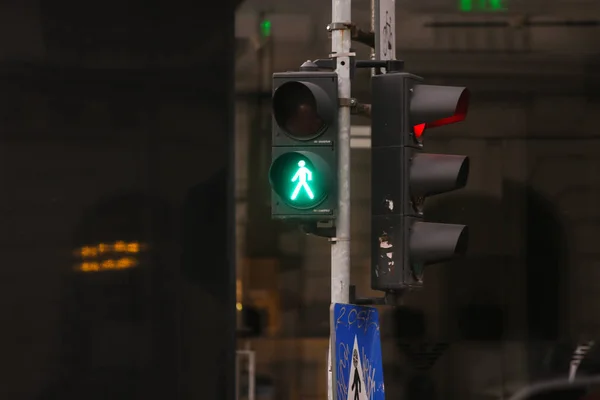 Green traffic light for pedestrians and red for cars on a city street and a crosswalk sign