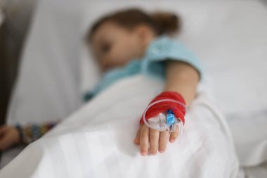 Hasta bir küçük kız elindeki bir kanül detaylarla 