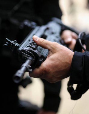 Otomatik tüfek tutan bir adamın elleriyle ayrıntılar