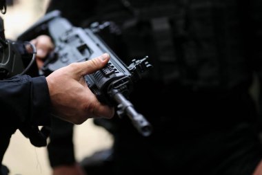 Otomatik tüfek tutan bir adamın elleriyle ayrıntılar