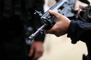 Otomatik tüfek tutan bir adamın elleriyle ayrıntılar