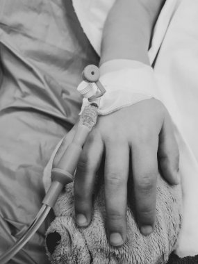 Siyah ve beyaz bir fotoğraf, küçük hasta bir kızın elinde.