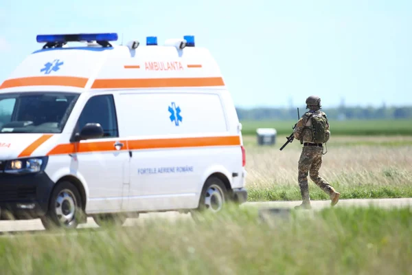 Un soldat de l'armée roumaine patrouille une base aérienne militaire, près d'un ambul — Photo