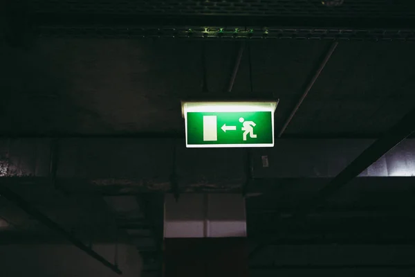 Close up of an exit this way sign inside an underground parking