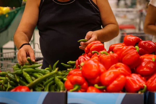 Podrobnosti o muži, který si vybírá horké zelené papriky (sladké červené papriky a — Stock fotografie
