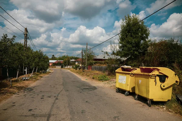 Vertederos amarillos de plástico en una calle del pueblo sin nadie alrededor — Foto de Stock