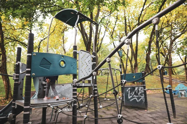 Kleines Mädchen beim Spielen und Klettern auf einem leeren Kinderspielplatz — Stockfoto