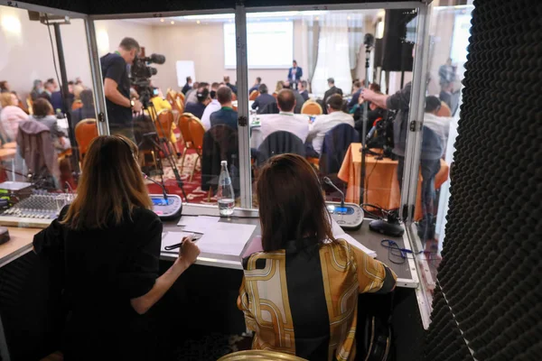 İki kadın çevirmen bir tercüme kabininde otururlar.