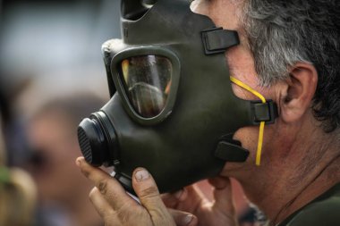 Yüzüne eski, eski bir askeri gaz maskesi takan bir adamın detayları..