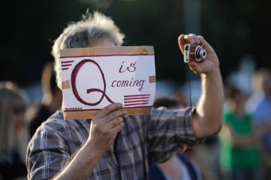 Bükreş / Romanya - 15 Temmuz 2020: Bir adam bir protestoda yer alıyor ve bir karton üzerinde Qanon mesajı sergiliyor.