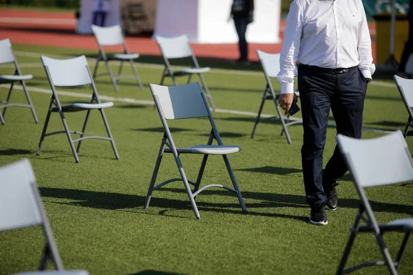 Chairs apart one from another to maintain the social distance during the Covid-19 outbreak at an outdoor event on the turf of a stadium.