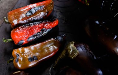 Kavrulmuş kırmızı biber ve patlıcanla ilgili detaylar açık hava metal sobanın üstünde odun ateşiyle.