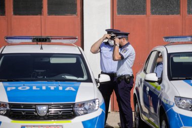 Bükreş, Romanya - 29 Temmuz 2020: Polis Gücü etkinliği sırasında maske takan Romen Polis memurları yeni Dacia arabalarının yanında poz verdiler.