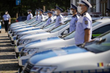 Bucharest, Romania - July 29, 2020: Romanian Police officers wearing masks pose next to new Dacia cars on display during an event of the Police Force. clipart