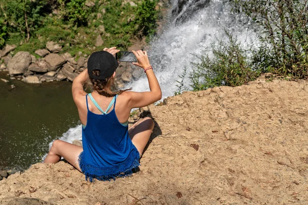 Junge Frau fotografiert Wasserfall mit Handy — Stockfoto