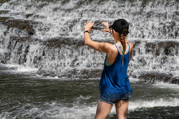 Junge Frau fotografiert Wasserfall mit Handy — Stockfoto