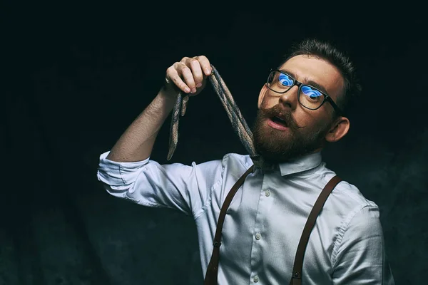 Jonge stijlvolle zakenman of manager houdt zijn stropdas in de hand alsof hij besloot te hangen zelf het conceptueel weergegeven: hoog niveau van stress en overwerk — Stockfoto