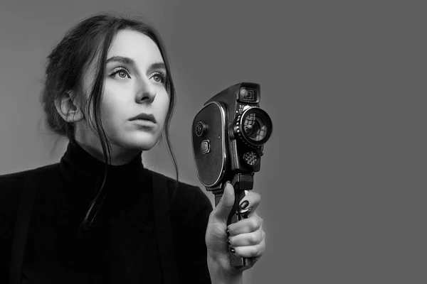 Крупный план портрета стильной молодой девушки, держащей старую винтажную камеру новшества в черно-белом цвете — стоковое фото
