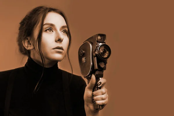 Крупный план портрета стильной молодой девушки, держащей старую винтажную камеру новшества в черно-белом тоне сепии — стоковое фото