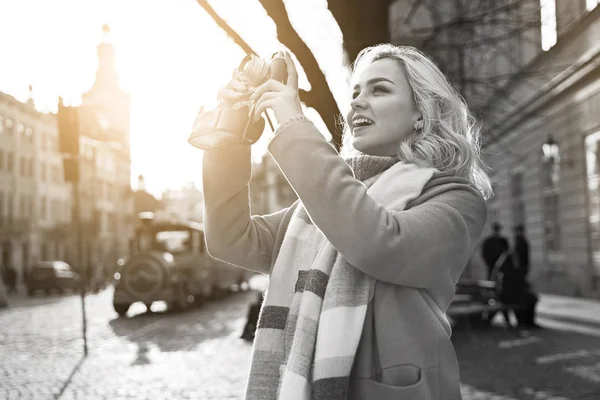 Jovem bela mulher loira alegre tirar fotos com sua câmera de filme vintage em um dia ensolarado na praça Rynok em Lviv, Ucrânia — Fotografia de Stock