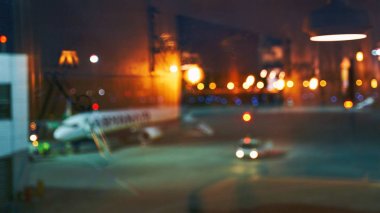 Bulanık ya da bulanık güzel havaalanı terminali sabah ya da akşam erken saatlerde uçak, bokeh ışıkları ve cam yansımalarla